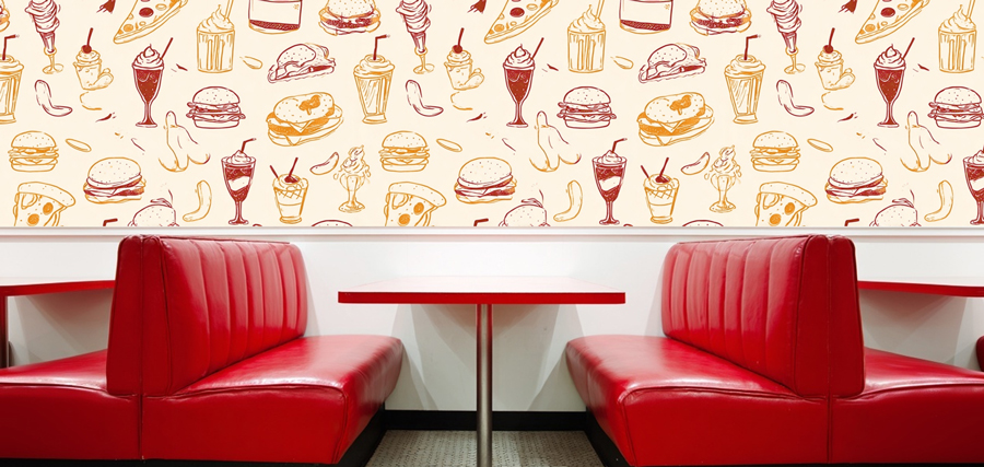 interior shot of a classic restarant booth with red leather seats and a custom pattern composed of burgers, pizzas and other fast foods adorning the walls.