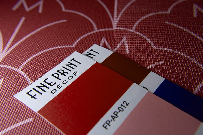 closeup photo of color swatches sitting on a wallpaper pattern rendered on two different materials
