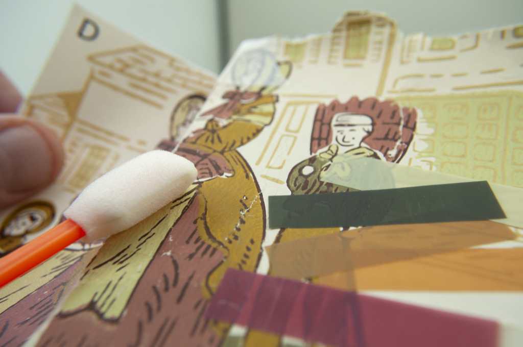 A wallpaper sample beside color books and the reprinted result