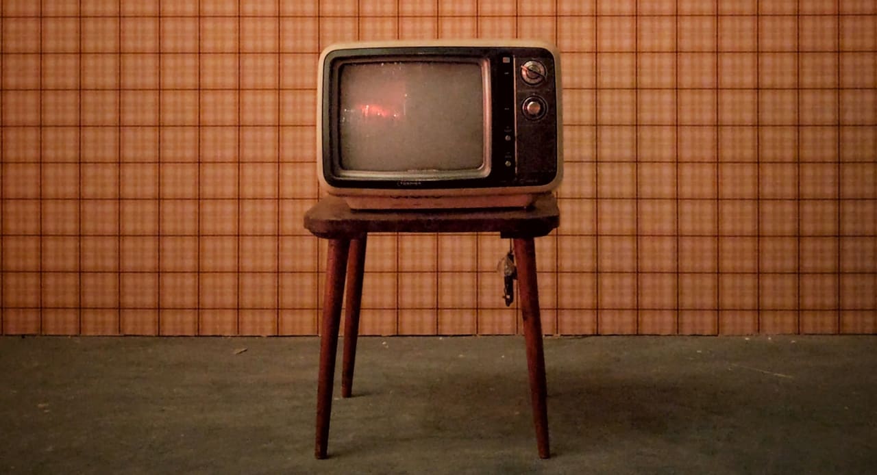Photo of old television in front of vintage wallpaper