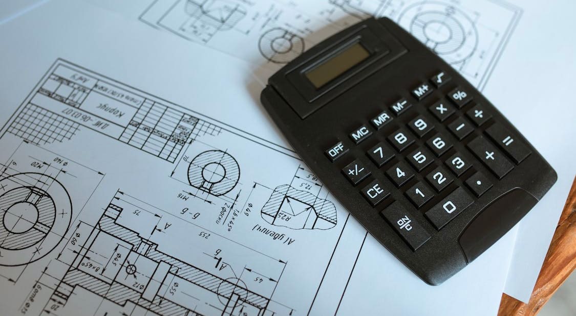 Photo of a calculator sitting on architectural blueprints