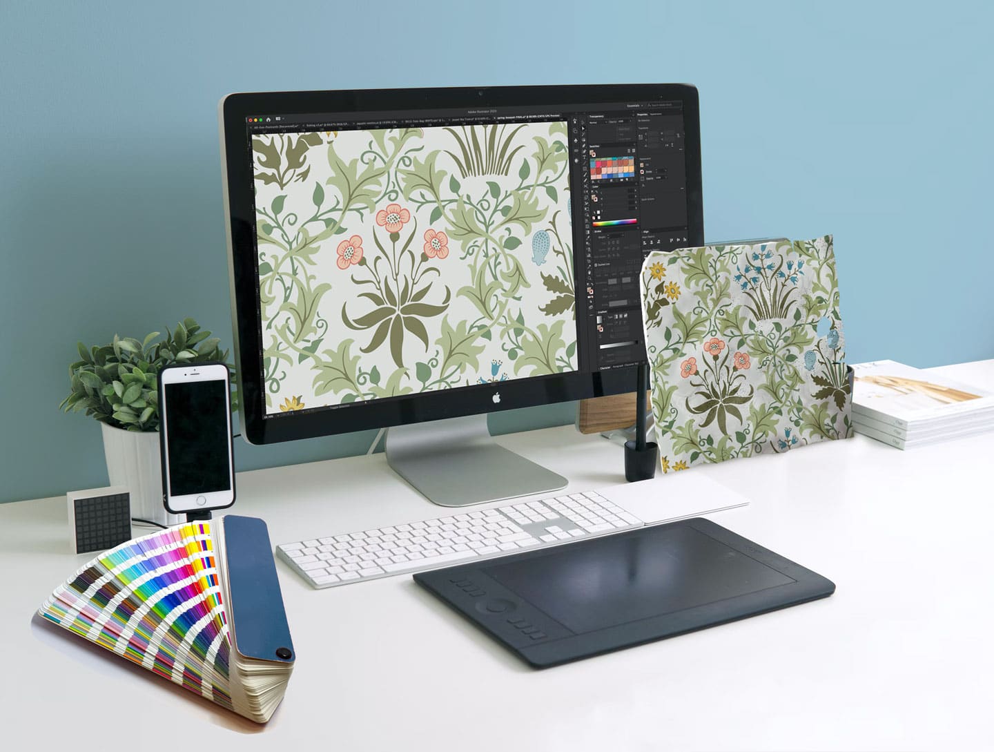 Image of a colorful wallpaper pattern on a computer display with the original sample leaning against the screen